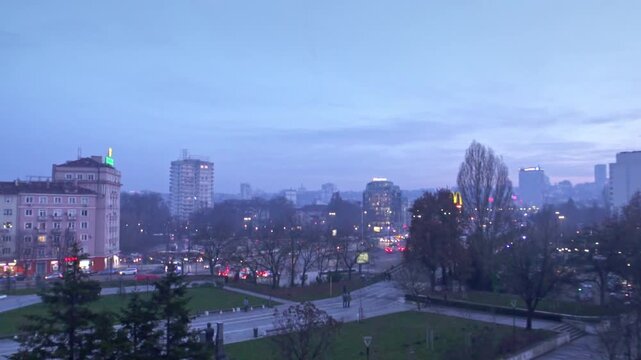 4K winter shot at dusk (evening) with beautiful pink and blue sky with trees, lights and the Vitosha mountain in the background in the city center of Sofia, Bulgaria in Eastern Europe.