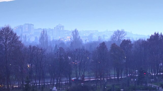 4K winter shot at dusk (evening) with beautiful pink and blue sky with trees, lights and the Vitosha mountain in the background in the city center of Sofia, Bulgaria in Eastern Europe.
