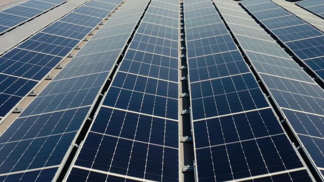 Long lines of rooftop solar panels extend across the frame, highlighting renewable power, technical order, and the sleek visual rhythm of large-scale energy infrastructure.
