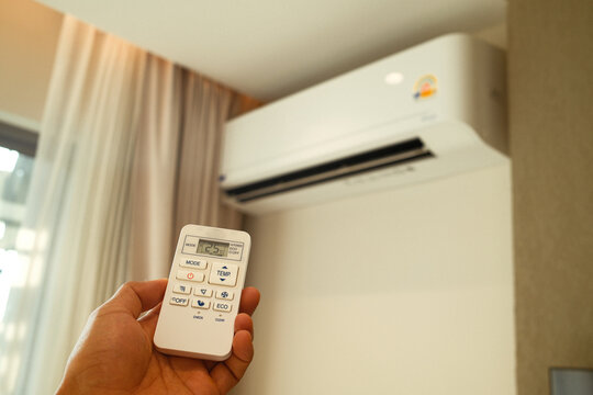 Man operating remote controller on Air conditioner inside the room, Air conditioner with remote controller