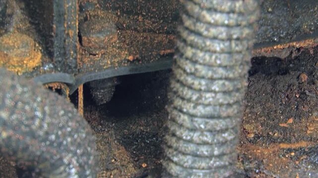 A meticulous gaze unveils the intricate details of a machinery's air intake system. Grime and rust adorn the metallic components, highlighting their worn resilience.