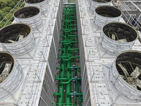 Aerial view of industrial cooling towers and green pipes.