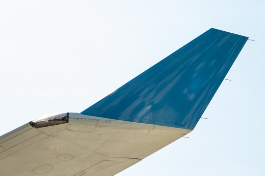 Close-up of blue aircraft winglet with navigation light against sky