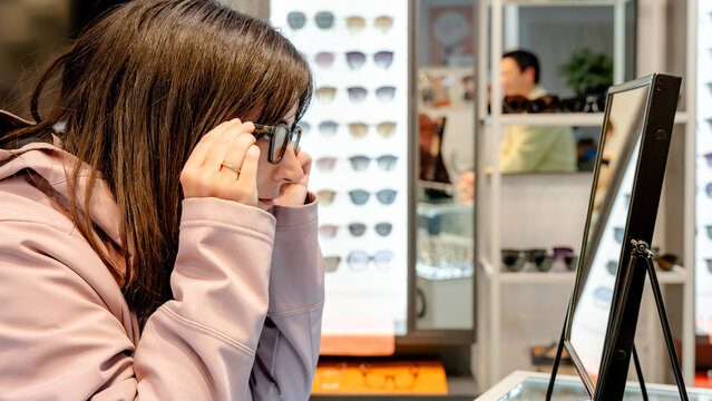 Customer choosing glasses in optical center mirror