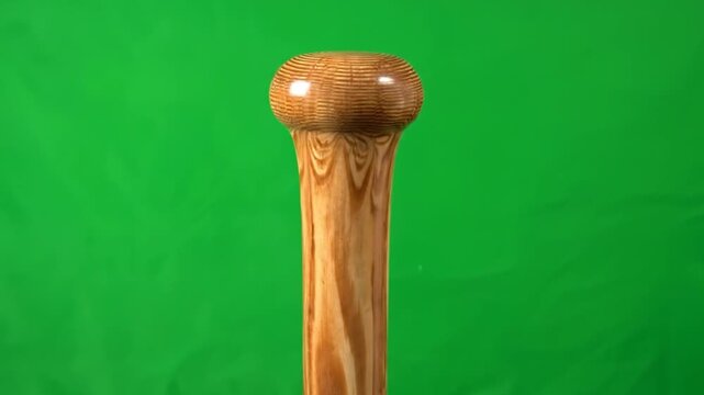 A close-up view of a wooden sports equipment handle, showcasing the natural wood grain and texture against a vibrant green backdrop