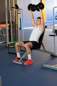 Young athlete lifting dumbbells in gym workout