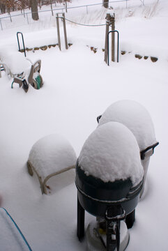 Snow covered backyard patio with barbecue grill in winter