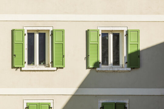 Sunlit facade with green window shutters