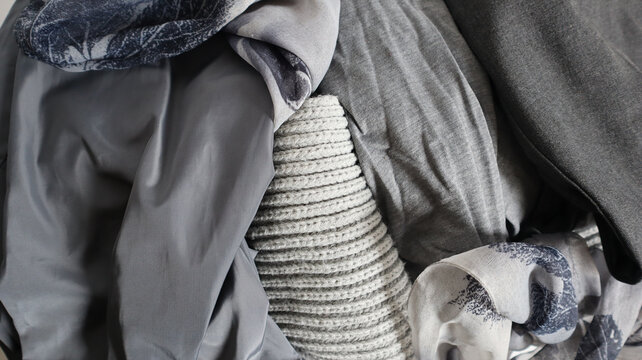 Different pieces of clothing are stacked together in a casual setting. The fabric includes various textures and colors. This picture captures the clutter of everyday wear.