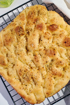 Homemade focaccia flatbread with herbs on cooling rack
