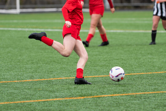 Female soccer player kicking ball during competitive match