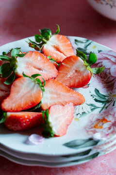 Fresh sliced strawberry on floral plate in spring light