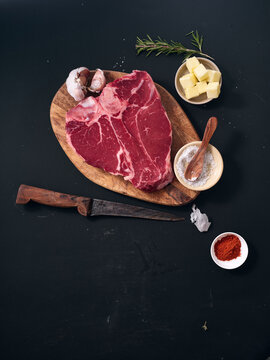 Raw t-bone steak with garlic and butter on cutting board
