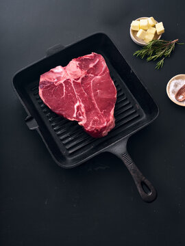 Raw t-bone steak in cast iron skillet with ingredients