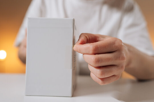 Female hands opening white electronics box to reveal new wireless console game controller, close-up unboxing scene capturing excitement, modern gaming lifestyle and gadget detail.