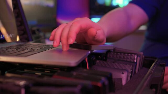 Professional IT technician working with external storage devices. Skilled IT professional performing quick data transfer on rugged external drives amidst ambient lighting