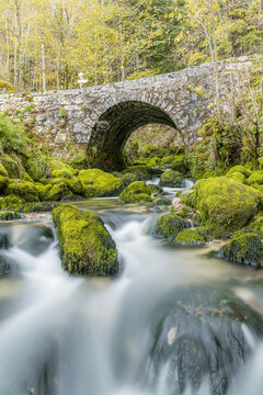 Long exposure waterfall beneath stone bridge in Lods, France