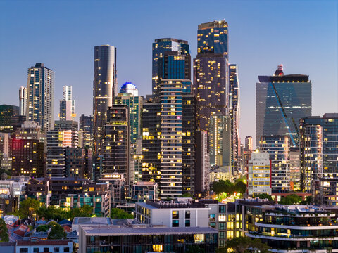 Aerial view of coloured lights on highrise buildings in a city skyline at twilight