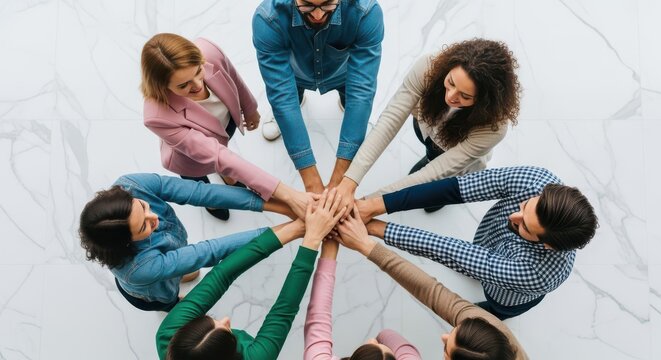 Diverse professionals gather together to stack their hands in a show of unity and collaboration.