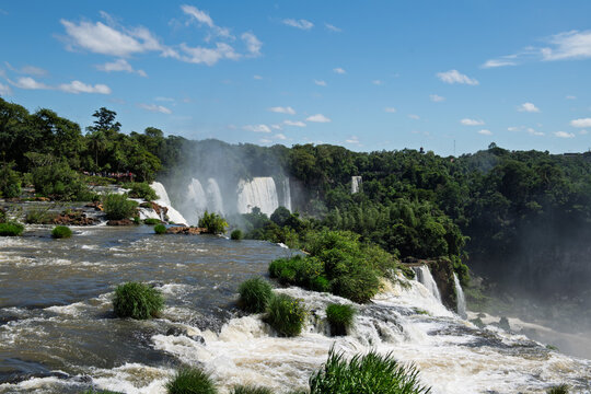Awe inspiring majestic iguazu falls river cascade in green forest under blue sky