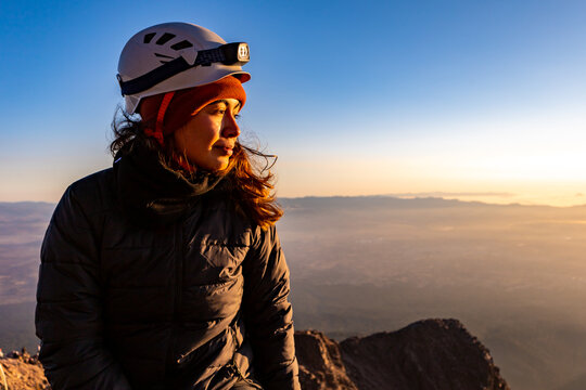 Sunrise mountain ascent with hiker in helmet at summit