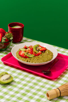 Matcha porridge with strawberry and kiwi on vichy cloth