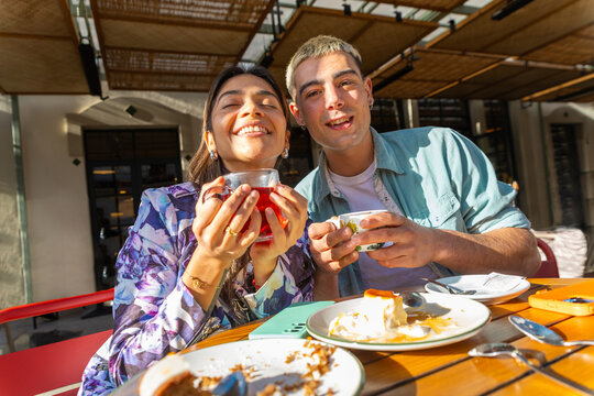 Friends enjoying drinks and dessert together on sunny terrace