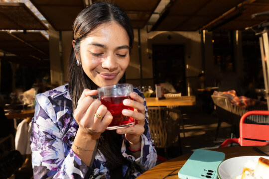 Woman enjoying hot tea on a sunny terrace cafe morning
