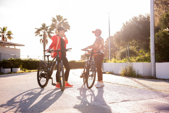 Friends pause with electric bicycles on a sunny street