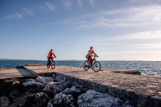 Women friends riding electric bicycles on seaside pier