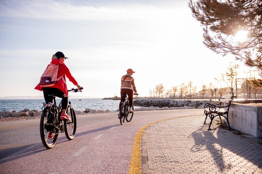 Friends riding electric bicycles on sunny seaside path