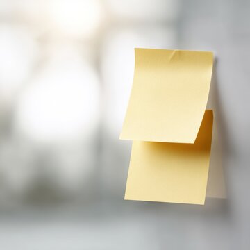 Two yellow sticky notes pinned together, office reminder concept on soft desk background
