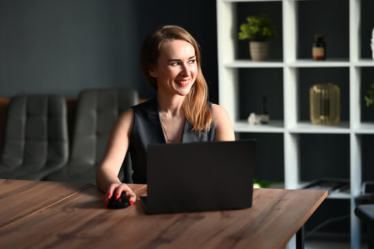 Smiling businesswoman working on laptop in modern office