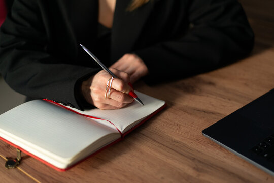 Woman writing business notes in notebook at work desk