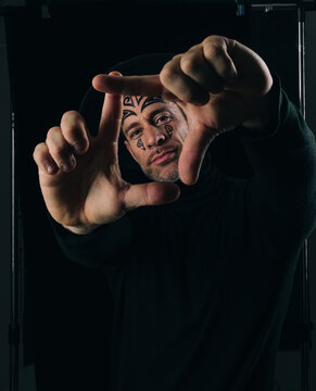 Tattooed man portrait framing shot with hands in dark studio