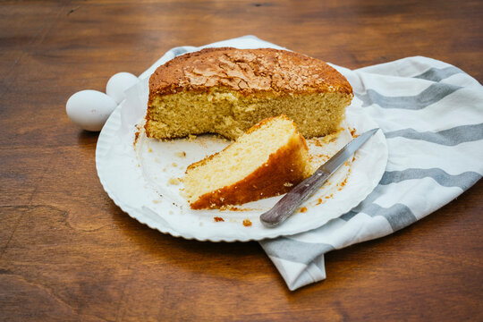 Homemade loaf cake slice on plate with knife and eggs