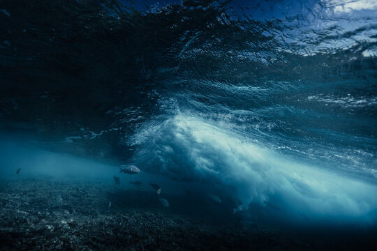 Underwater ocean wave with fish near a Maldives island reef
