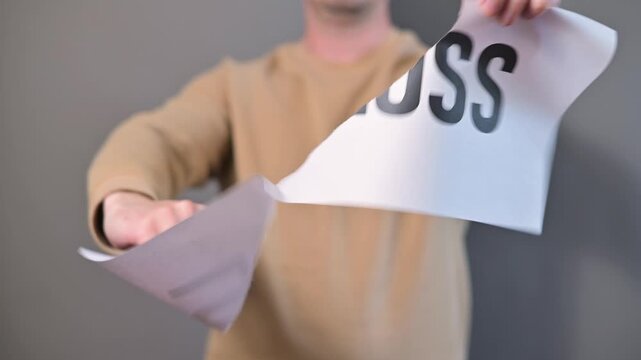 A person grabs a piece of paper with the word loss written on it and tears it in half in a private space. The action represents an emotional response to feelings of grief and parting