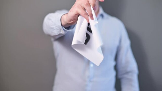 A person is holding a sign that reads deficit and then crumples up paper to throw it away. This action symbolizes financial challenges and decision-making processes in a neutral indoor environment