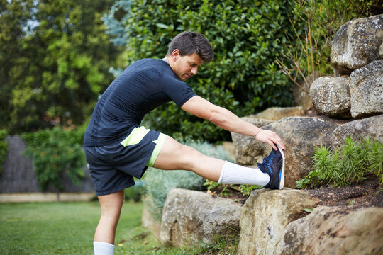 Man stretching leg on rock outdoors during fitness training