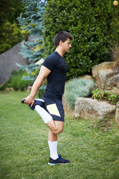 Man stretching quadriceps outdoors before fitness training