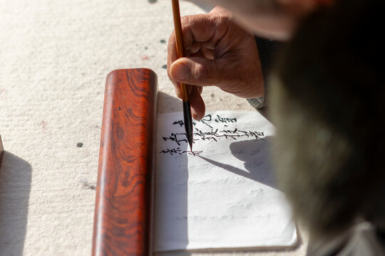 Elderly hand practicing Chinese calligraphy with brush