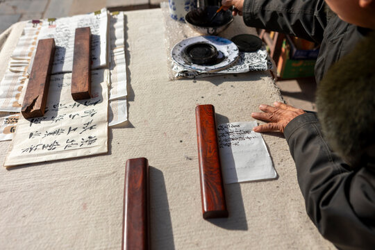 Elderly hands practicing Chinese calligraphy with ink tools