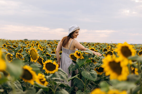 Woman walking through sunflower field at golden hour