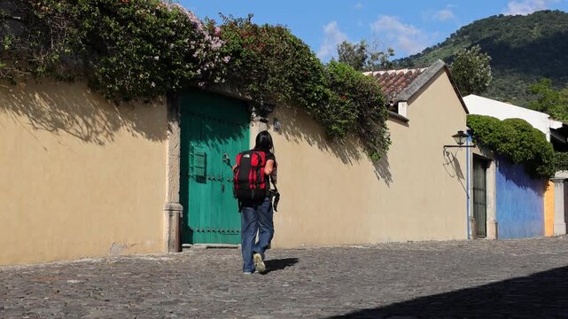 backpacker walking down scenic colonial street in antigua guatemala (backpacking latin america with large backpack) book bag back pack spanich architecture scenic tropical city