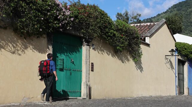 backpacker walking down scenic colonial street in antigua guatemala (backpacking latin america with large backpack) book bag back pack spanich architecture scenic tropical city