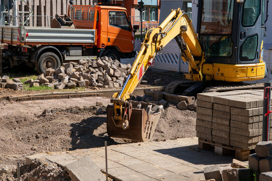 New parking lot construction in the city with an excavator and concrete blocks at a construction site
