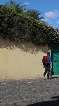 backpacker walking down scenic colonial street in antigua guatemala (backpacking latin america with large backpack) book bag back pack spanich architecture scenic tropical city