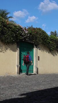 backpacker walking down scenic colonial street in antigua guatemala (backpacking latin america with large backpack) book bag back pack spanich architecture scenic tropical city