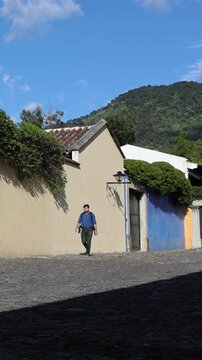 backpacker walking down scenic colonial street in antigua guatemala (backpacking latin america with large backpack) book bag back pack spanich architecture scenic tropical city